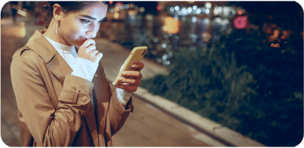 A young girl is looking at her smartphone in the street.